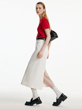 A lady wears a red top and a white maxi skirt.